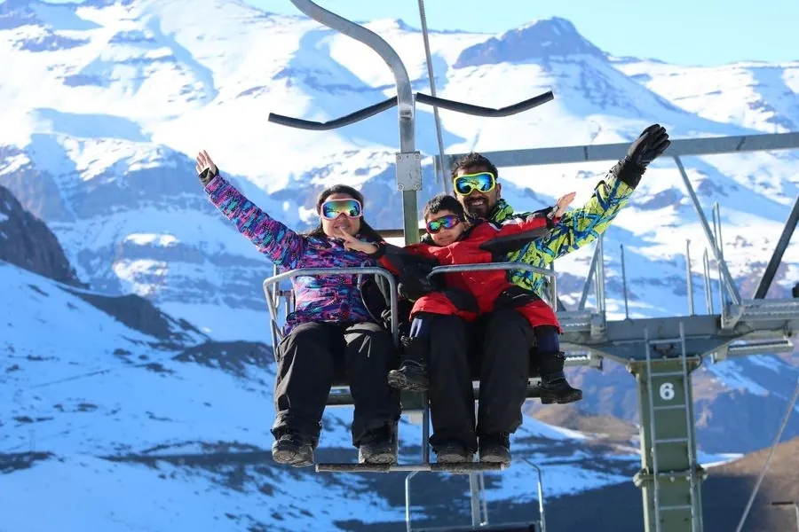 Family on a chairlift with snowy mountains behind