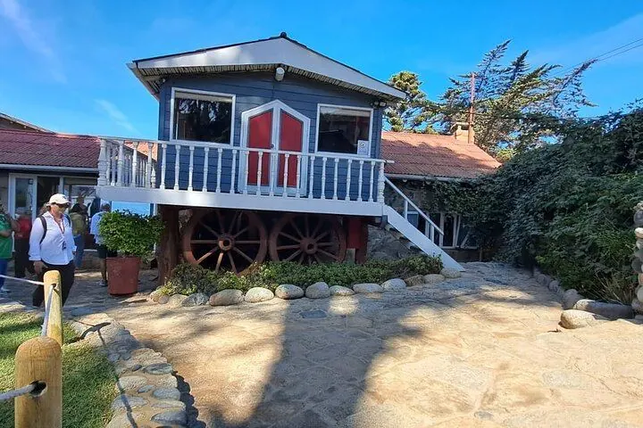 Blue wooden house with old wheels and a stone courtyard