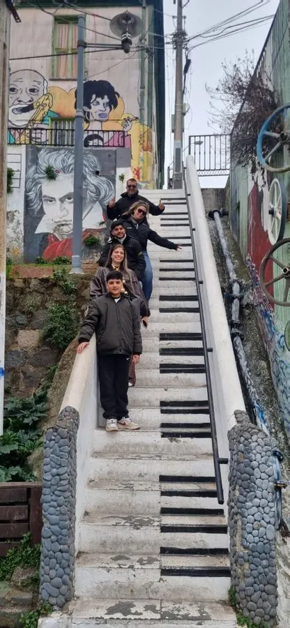 Travelers on a piano-key staircase with murals in Valparaíso