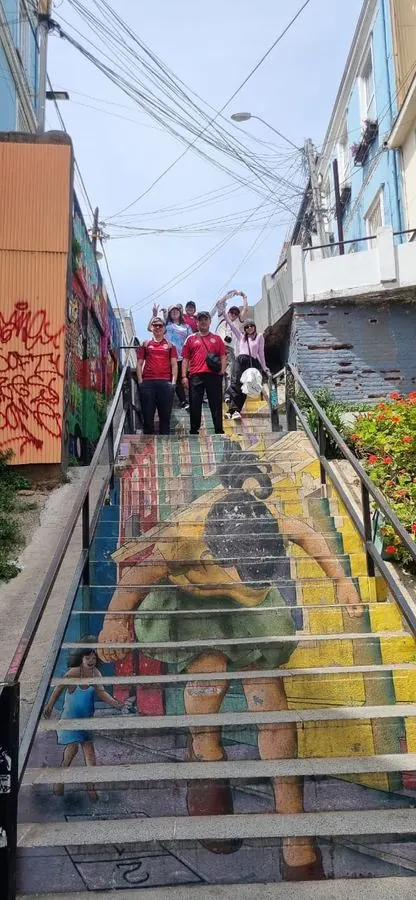 Travelers on a staircase with a giant mural in Cerro Concepción, Valparaíso