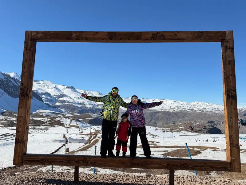 Family in a giant wooden frame with a view of the snow slopes, Farellones, Chile
