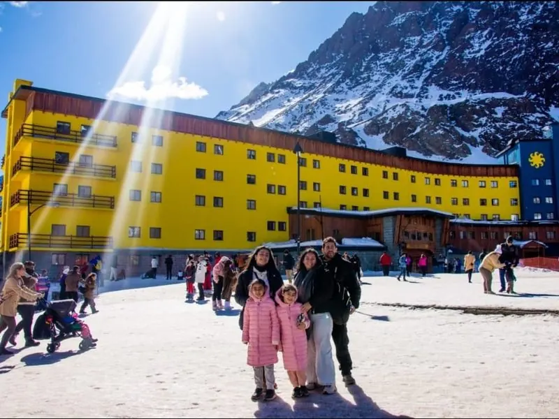 Family in front of the Portillo hotel with the snow-capped Andes behind, Chile