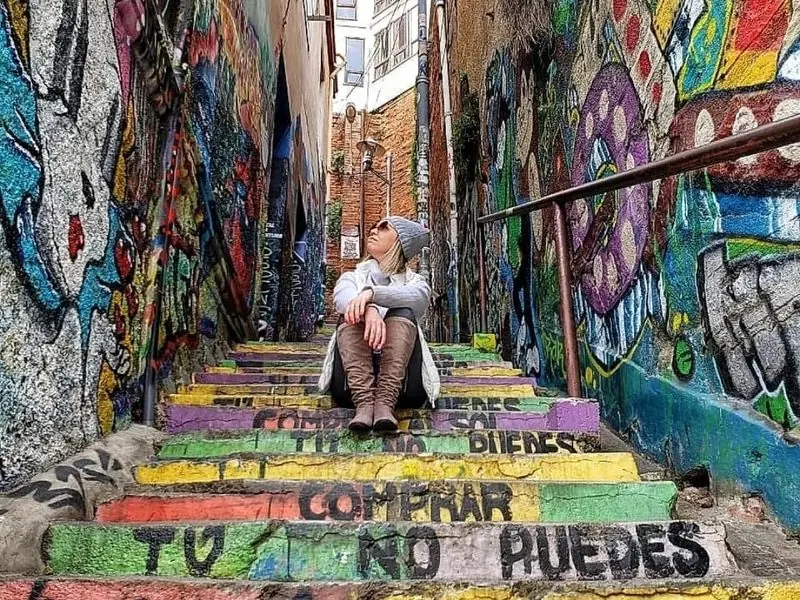 Traveler sitting on a graffiti-covered staircase in Valparaíso, Chile