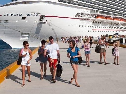 Cruise passengers walking along the pier next to a large cruise ship