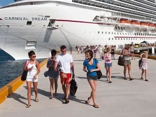 Cruise passengers walking along the pier next to a large cruise ship